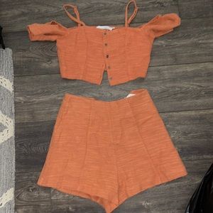 This is a woven orange matching set. With a crop top and shorts.